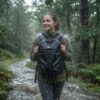 Vrouw wandelt in hevige regen met een waterdichte FireMat-rugzak in het bos